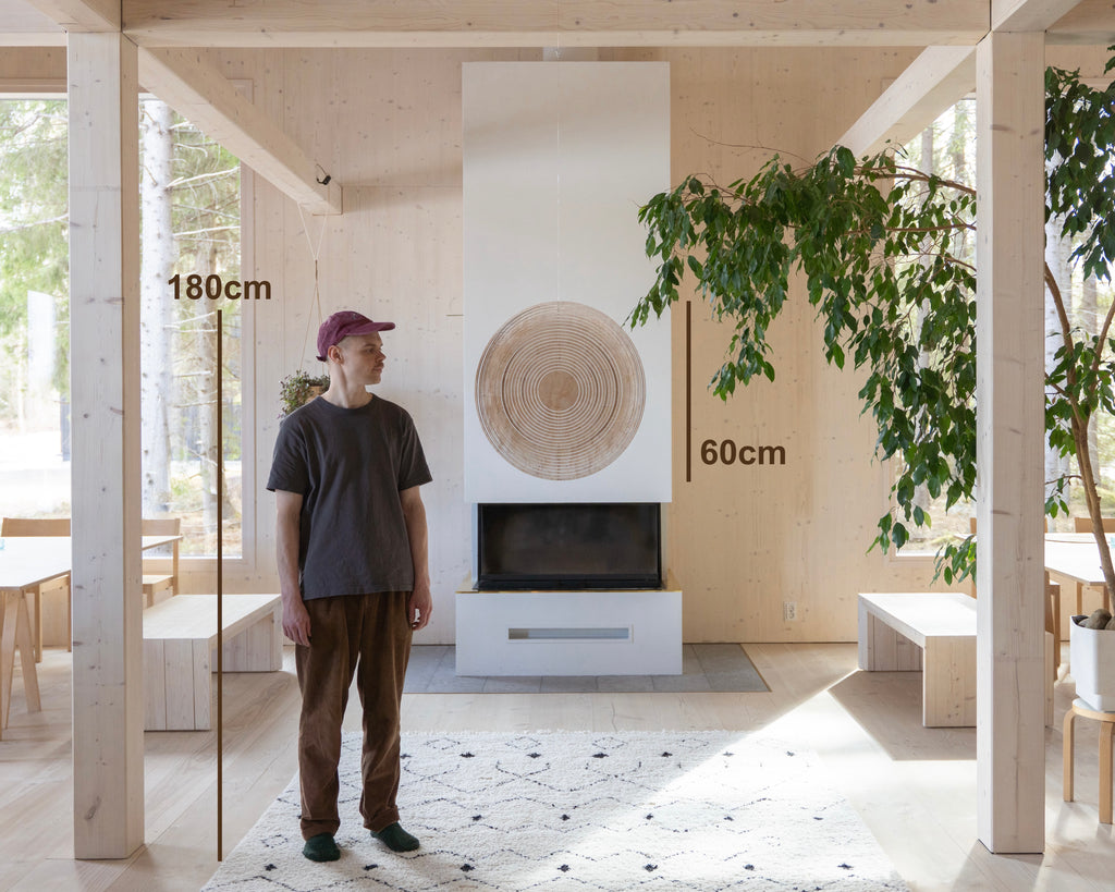 Person stands near Cycloop 60 in a naturally lighted room with plants fireplace and big windows