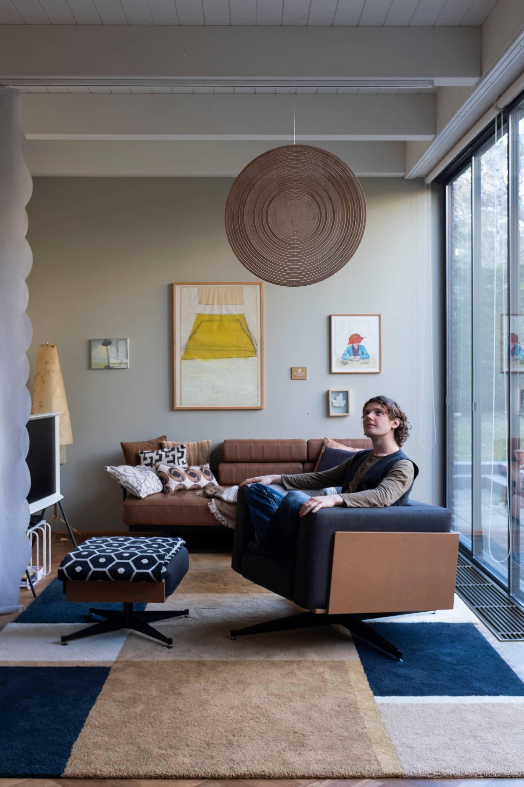 Cycloop-in-a-living-room-with-calm-grounding-colours-natural-light-and-happy-young-man-observing-the-hanging-design