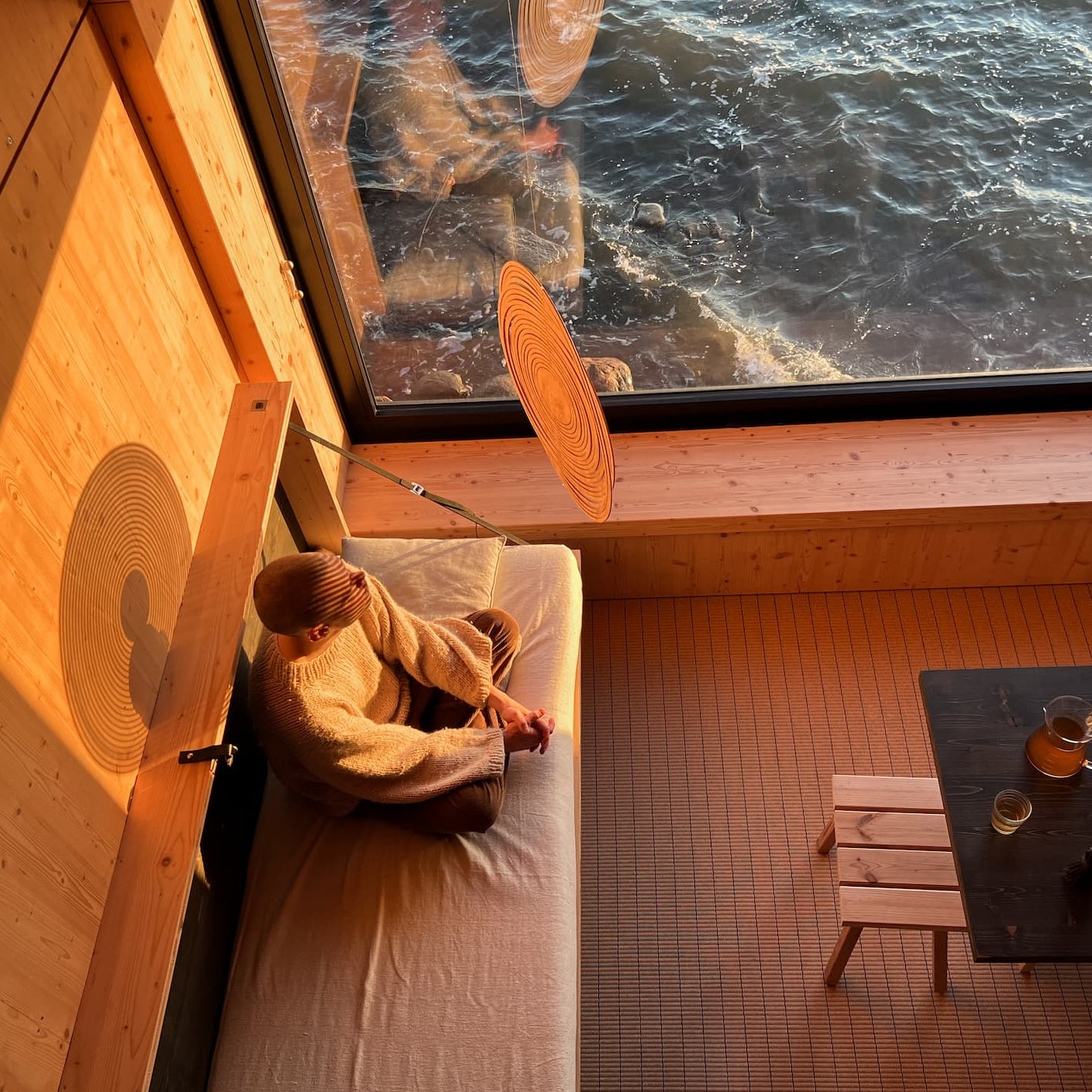 Man-sits-in-a-cozy-position-looking-at-the-Cycloop-in-a-grounding-room-with-sunset-shadow
